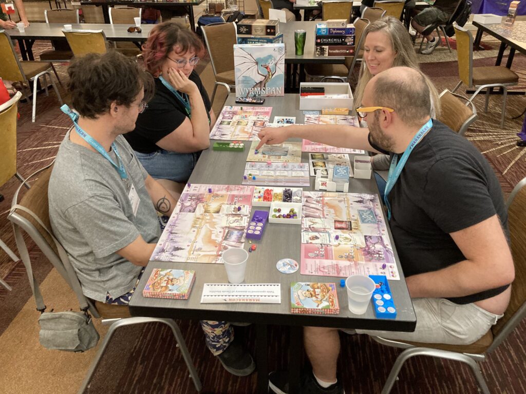 Four players playing Wyrmspan. 